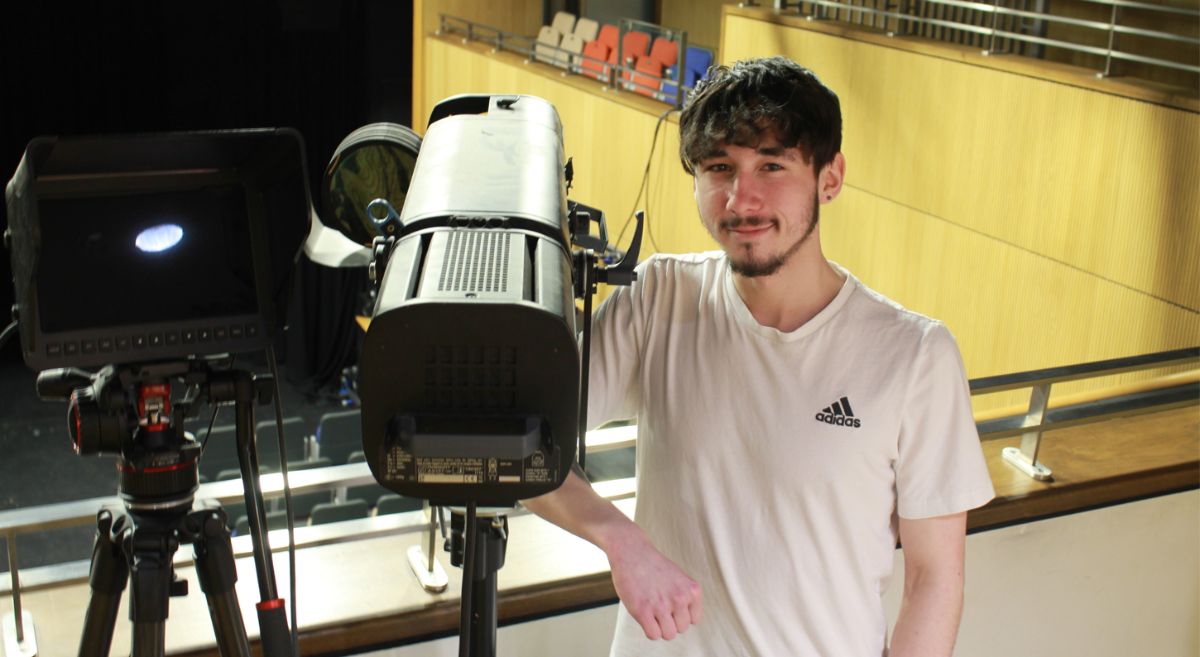 Picture of Ryan Gibson standing beside theatre equipment with a theatre in the background.